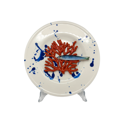 Koraal piccolo met sardientje op wit bord met blauwe verfspetters, 21 cm rond.
