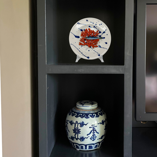 Koraal piccolo met sardientje op wit bord met blauwe verfspetters, 21 cm rond.
