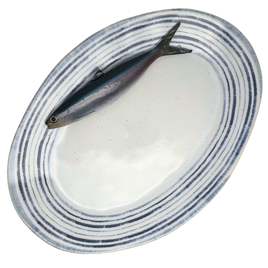 Haring/Alaccia op een groot ovaal serveerbord met blauw gestreepte rand.